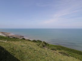 A view of the sea and shoreline with grass and rocks at Puffin Way Holiday Caravan