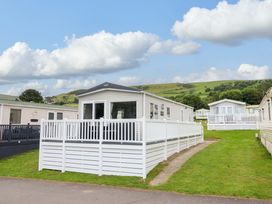 A caravan with decking and grass area at 8 Puffin Way Llwyngwril