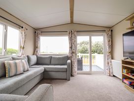 A living room with a sofa and television at 8 Puffin Way Llwyngwril
