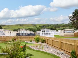 An outdoor area with caravans and landscaped gardens at 8 Puffin Way in Llwyngwril