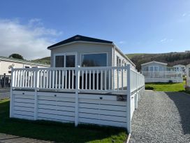 A mobile home with a deck and gravel path at 8 Puffin Way Llwyngwril
