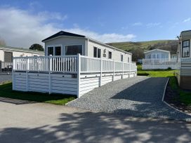 An outdoor view of a static caravan with decking at 8 Puffin Way in Llwyngwril