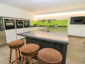 A kitchen with stovetop, stools, ovens and sink at Silver Copse Frilford Heath Near Abingdon