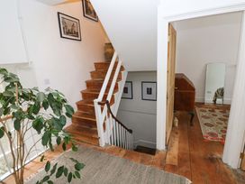 A hallway with a staircase and a plant at 18 Main Street