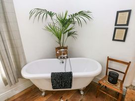 A bathroom with a bathtub and plant at 18 Main Street