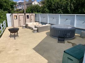 An outdoor area with a hot tub, seating, and storage sheds at 1 Bryn Beudy, Narberth