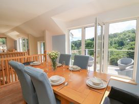 A dining room with a table set and large windows at 1 Bryn Beudy in Stepaside