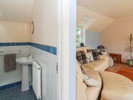 A bathroom with sink and towel next to a living room with sofa and table at 1 Bryn Beudy Stepaside