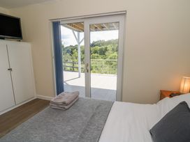 A bedroom with a bed and sliding doors leading to a balcony at 1 Bryn Beudy Stepaside
