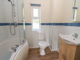 A bathroom with a shower, bathtub, toilet and sink at 1 Bryn Beudy Stepaside