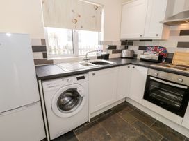 A kitchen with appliances including a refrigerator and washing machine at 3 Riverside Bungalows Llanbedr