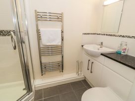 A bathroom with a shower, sink, mirror, and towel rail at 3 Riverside Bungalows Llanbedr