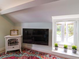 A living room with a television and a clock at Sea Sanctuary 