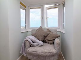 A snug area with an armchair and windows at Sea Sanctuary