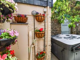 An outdoor area with flower baskets and a hot tub at Sea Sanctuary in 