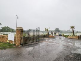 A gated entrance with a sign and palm trees at Hentland Farm in Kidlington