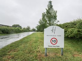 A sign for Heathfield Park near a road with trees and grass in Kidlington