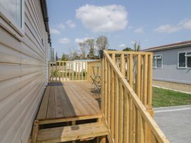 A wooden deck with a chair and railing at Pinewood in Kidlington