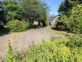 A garden with flowers and a stone building at Carreg Las in Haverfordwest