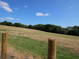 An open field with a fence post and trees at Dingle in Kidderminster