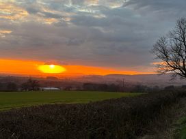 A landscape with a sunset over hills and a field