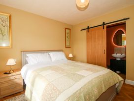 A bedroom with a bed and a sliding door leading to a bathroom at Dingle in Cleobury Mortimer