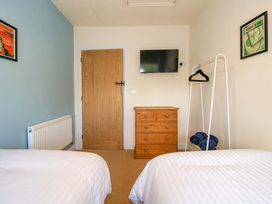 A bedroom with two beds, a television, and a dresser at Dingle in Cleobury Mortimer