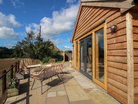 An outdoor patio with seating and planters at Dingle in Cleobury Mortimer
