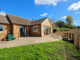 A wooden house with a patio and garden furniture at Dingle in Cleobury Mortimer