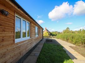 A wooden exterior wall with windows and a pathway at Dingle in Cleobury Mortimer