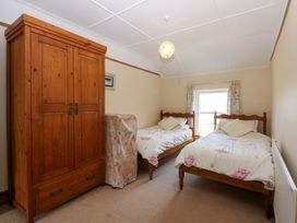 A bedroom with two beds and a wardrobe at Disgwylfa in Sarn Mellteyrn