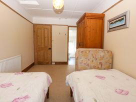 A bedroom with two beds and a wardrobe at Disgwylfa Sarn Mellteyrn