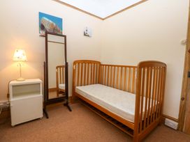 A bedroom with a crib and a mirror at Disgwylfa Sarn Mellteyrn