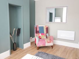 A living room with an armchair and a mirror at Flat 1A, Mona House in Conwy