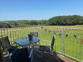 An outdoor balcony with a table and chairs at Hayes Lodge Coach House in Chulmleigh