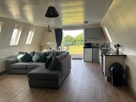 A living room with a sofa and kitchen area at Hayes Lodge Coach House, Chulmleigh