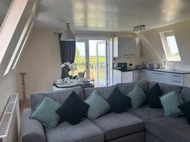 A living room with a sofa and kitchen area at Hayes Lodge Coach House in Chulmleigh