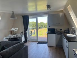 A living room with a sofa and kitchen units at Hayes Lodge Coach House in Chulmleigh