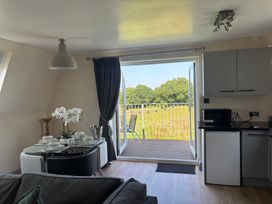A living room with a table set for dining and a balcony view at Hayes Lodge Coach House Chulmleigh
