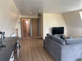 A living room with a sofa and television at Hayes Lodge Coach House in Chulmleigh