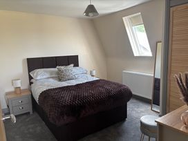 A bedroom with a bed, bedside table, and mirror at Hayes Lodge Coach House, Chulmleigh