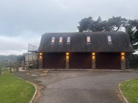 A garage with multiple doors and windows at Hayes Lodge Coach House Ashreigney near Dolton