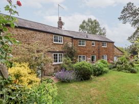 A brick house with garden and plants at Magdalen Cottage, Hook Norton