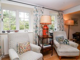 A living room with armchairs and a lamp at Magdalen Cottage in Hook Norton