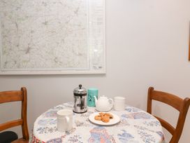 A dining room table with a map on the wall at Magdalen Cottage in Hook Norton