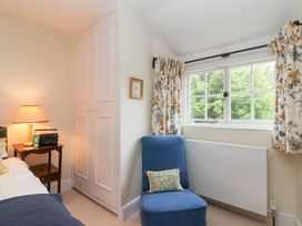 A bedroom with a bed, lamp, and armchair at Magdalen Cottage in Hook Norton