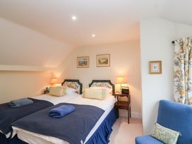 A bedroom with two beds and a chair at Magdalen Cottage in Hook Norton