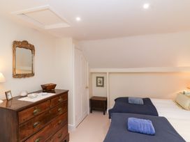 A bedroom with two beds and a dresser at Magdalen Cottage in Hook Norton