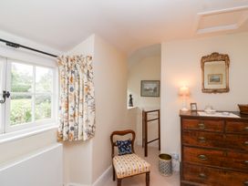 A room with a window, chair, and chest of drawers at Magdalen Cottage, Hook Norton