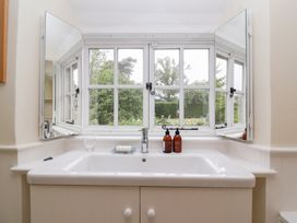 A bathtub with a window in the bathroom at Magdalen Cottage in Hook Norton